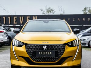 Front view of a yellow car parked in an outdoor showroom setting.
