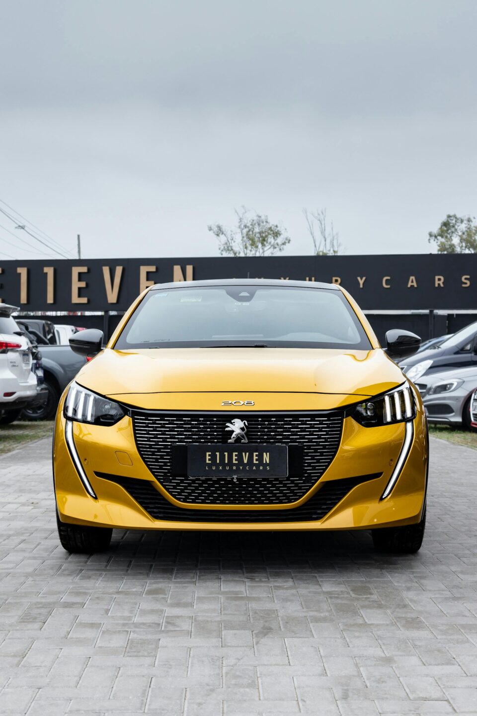 Front view of a yellow car parked in an outdoor showroom setting.