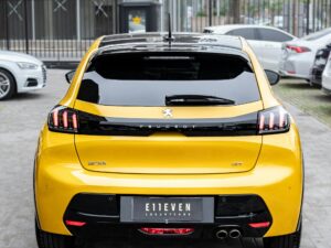 Rear view of a yellow Peugeot 208 GT parked in an urban environment.