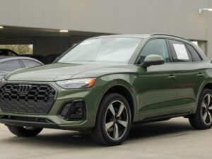 Modern khaki green 2024 Audi Q5 SUV parked in an urban parking lot, showcasing sleek automotive design.