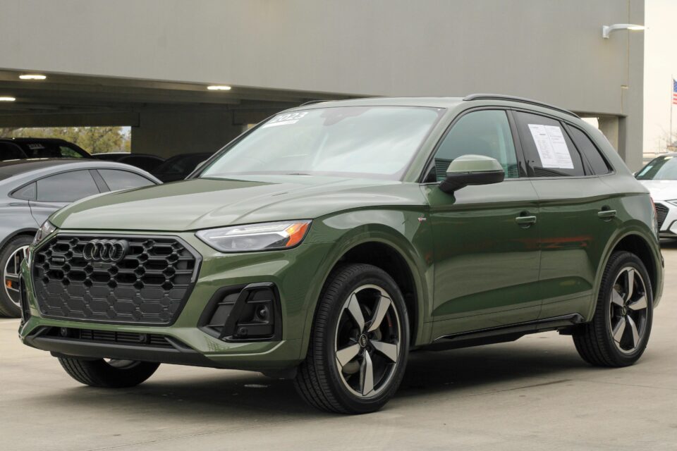 Modern khaki green 2024 Audi Q5 SUV parked in an urban parking lot, showcasing sleek automotive design.