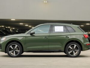 Detailed side view of a green luxury SUV in an indoor urban parking space.